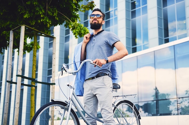 Luxury bearded male in a sunglasses on a bicycle in a downtown.