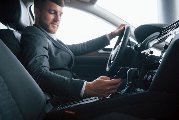 Luxury interior. Modern businessman trying his new car in the automobile salon