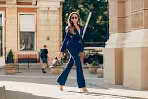 Foto gratuita la donna ricca di lusso si è vestita in vestito blu alla moda elegante che cammina nella città il giorno soleggiato di autunno che tiene la borsa