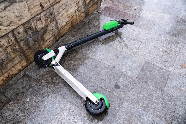 Lying electric scooter for sharing on the wet ground at cloudy weather in Bucharest, Romania