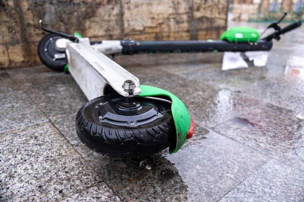 Lying electric scooter for sharing on the wet ground at cloudy weather in Bucharest, Romania