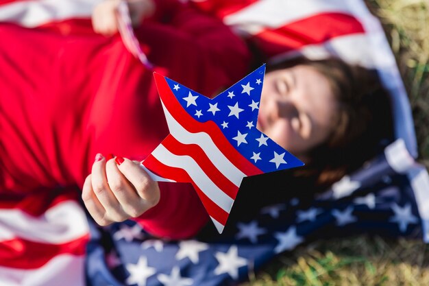 Lying woman holding USA flag star and looking at camera