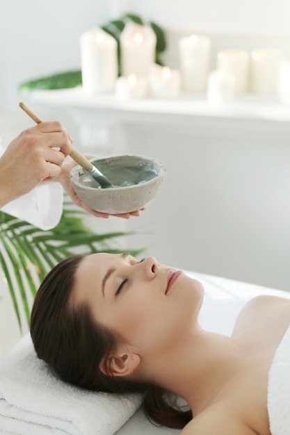 Lying woman receiving a facial beauty treatment.