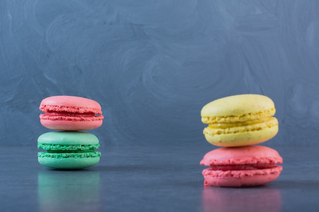 Macaroni cookies of different colors on a dark-gray surface