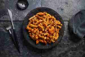 Free photo macaroni noodles with meat and tomato sauce served on plate on table