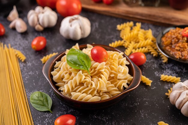 Macaroni sauteed with tomatoes and basil on a gray plate.