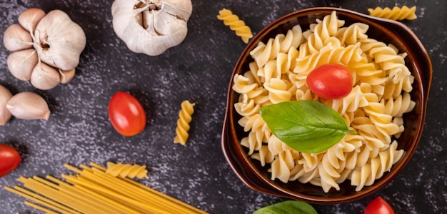 Maccheroni saltati con pomodori e basilico su un piatto grigio.