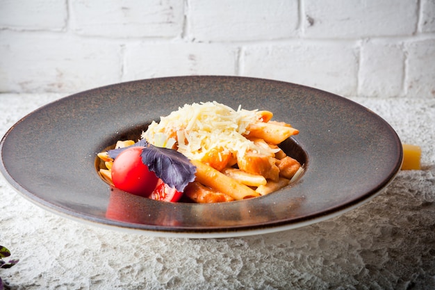 макароны с сыром и помидорами и фиолетовым базиликом в круглой тарелке