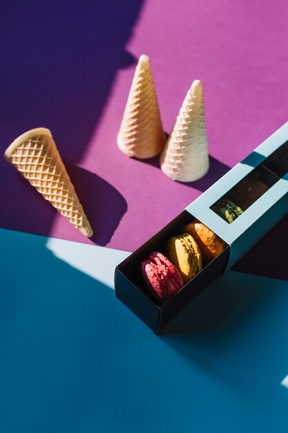 Macaroons in the box with an empty waffle cones over dual backdrop