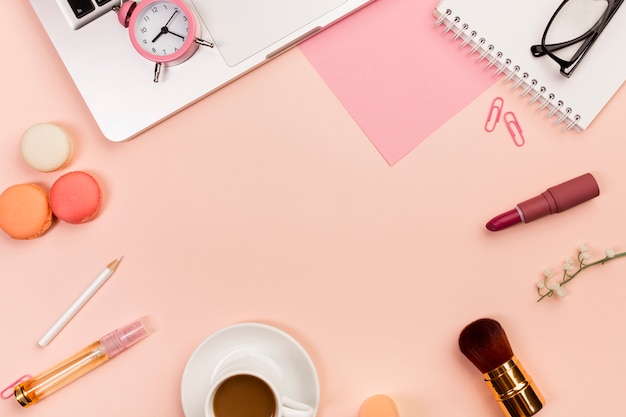 Macaroons,coffee cup,makeup brushes,alarm clock,laptop on peach colored background