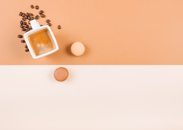 Macaroons; coffee cup; and roasted coffee beans on dual background