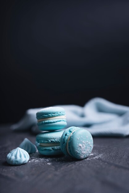 Macaroons and eclairs with lavender flowers on black rock textured background