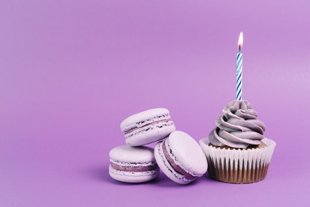 Macaroons near cupcake with candle