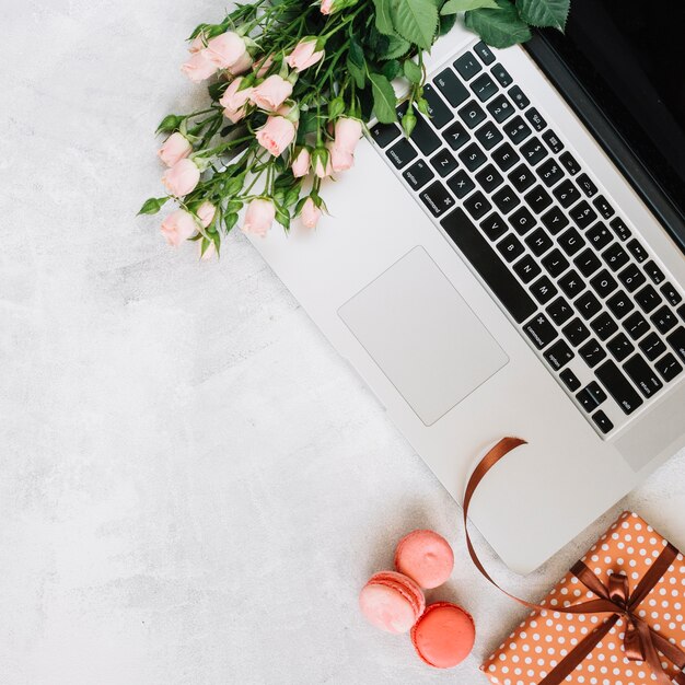 Macaroons and present near flowers and laptop