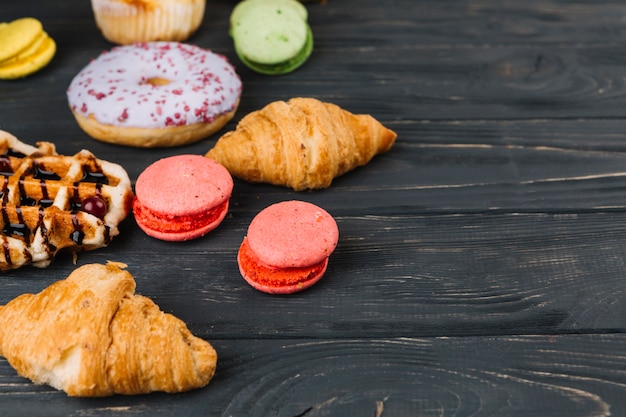 Macaroons; waffles; croissant and donuts on wooden table