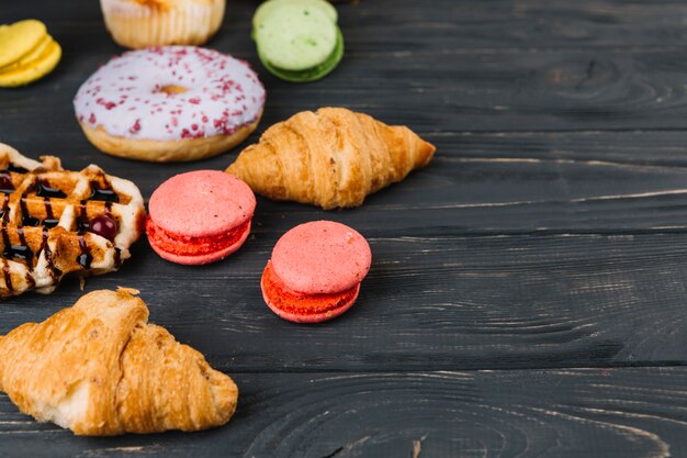 Macaroons; waffles; croissant and donuts on wooden table