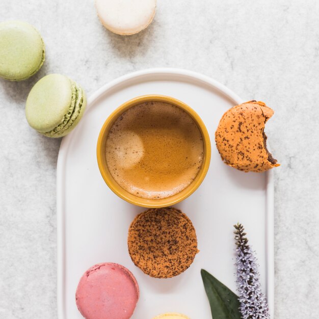 Macaroons with coffee cup on plate over the marble backdrop