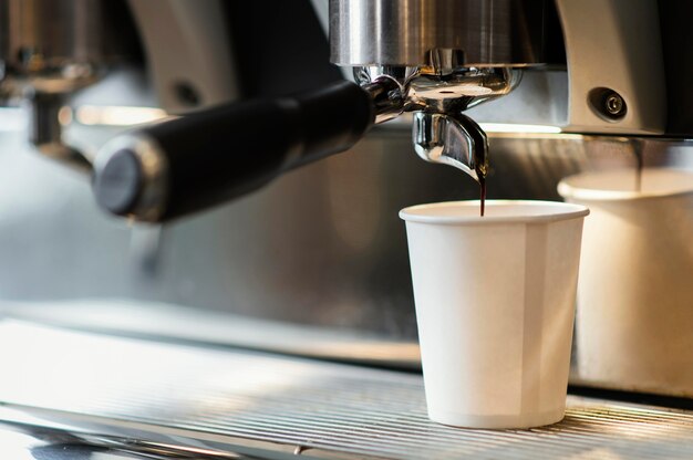 Machine pouring coffee in disposable cup
