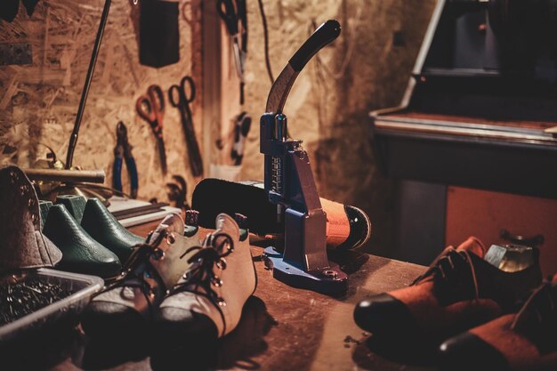 Machine tool on the table with shoes for making holes for laces at cobbler's workshop.