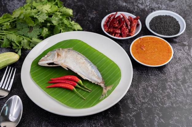 Mackerel placed on banana leaves on a white plate.