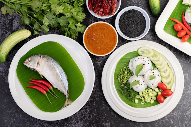 Mackerel placed on banana leaves on a white plate.