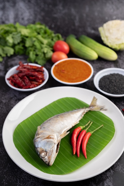 Free photo mackerel placed on banana leaves on a white plate.