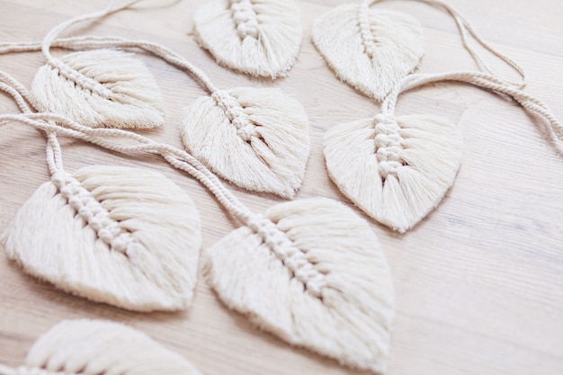 Macrame leaves in natural color on the wooden background. cotton rope decor macrame to make your home more cozy and unique. woman hobby.