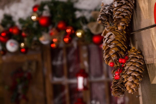 집 안에 나무 벽에 매달려 빨간 체리와 매크로 갈색 소나무 콘 크리스마스 장식.