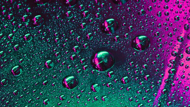 Macro of green and pink water drops on the surface