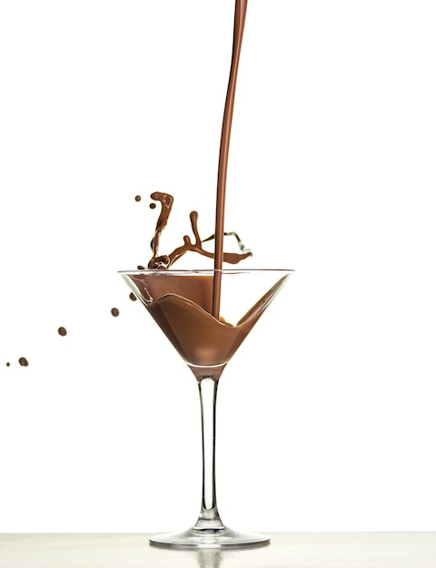 Макро-съемка с горячим шоколадом, падающим в стакан на белой стене в студии