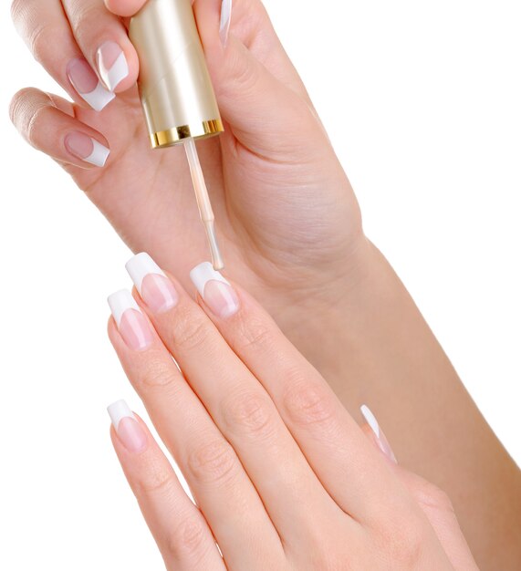 Macro shot of female hands  applying clear nail vanish on her fingernails 