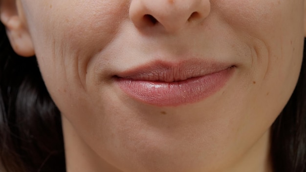 Macro shot of female model smiling and moving lips on camera, showing white teeth and candid smile. Happy woman with beautiful mouth and facial expressions, natural skin. Close up.