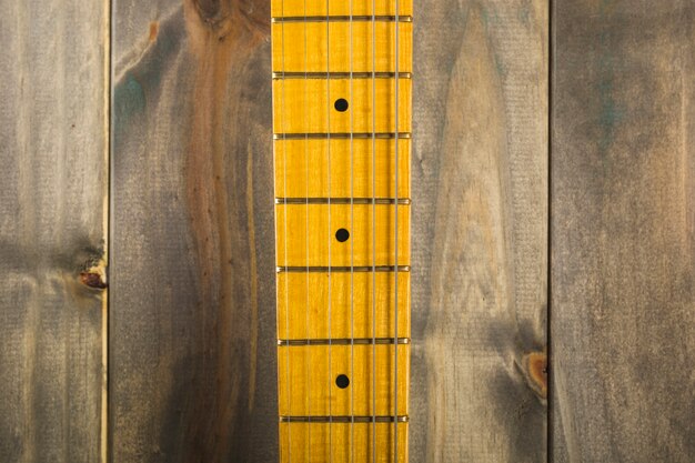 木製の背景にギターの弦とフレットボードのマクロショット