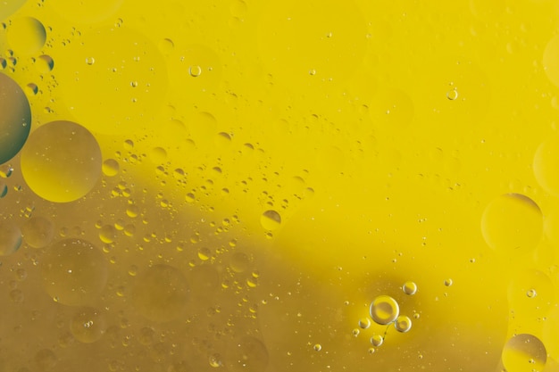 Macro shot of oil mixed with water on yellow background