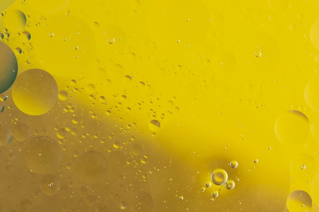 노란색 배경에 물 혼합 기름의 매크로 촬영