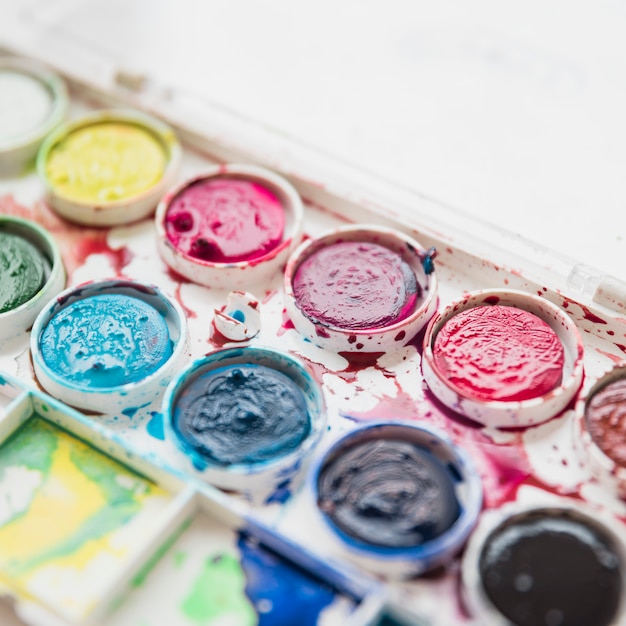 Foto gratuita colpo a macroistruzione di una casella della gamma di colori della pittura con l'acquerello bagnato sporco