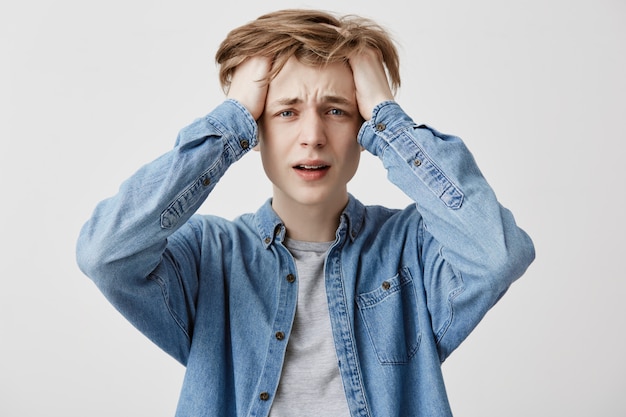 Foto gratuita il pazzo pazzo che si rammarica per gli errori, vestito con una camicia di jeans, capisce che non può cambiare nulla o tornare indietro per migliorare la situazione, essere nel panico e nello stress. grande disperazione