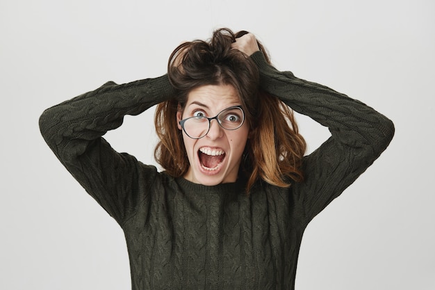 Foto gratuita la donna pazza pazza scompiglia i capelli e urla di rabbia, indossa occhiali storti