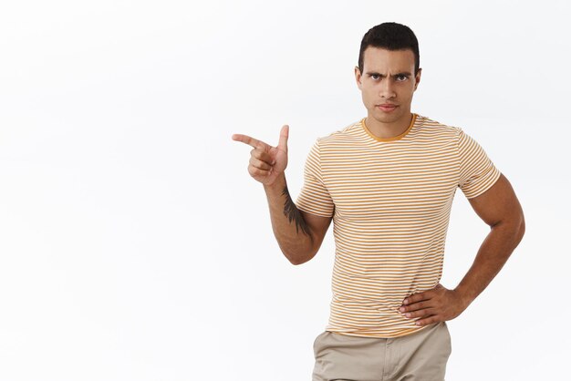 Mad, disappointed masculine man deal with personal mistakes, pointing finger left at empty white space