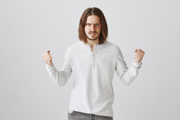 Free photo mad guy clench fists in anger, looking determined