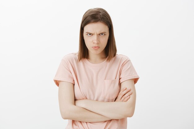 Mad and offended sulking woman looking from under forehead, cross arms chest defensive