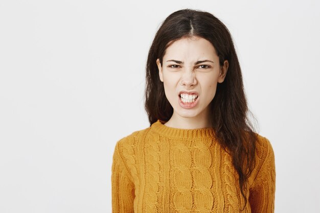 Mad and outraged grimacing girl clench fists and looking with hatred