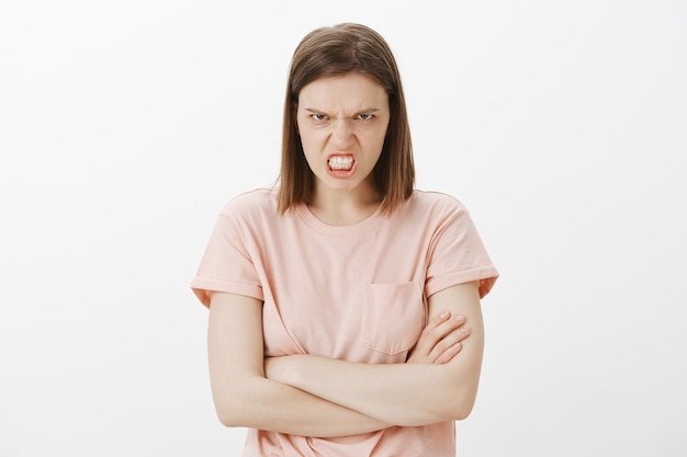 Mad and outraged young woman looking with scorn and hatred, clench teeth and cross arms chest, hate someone