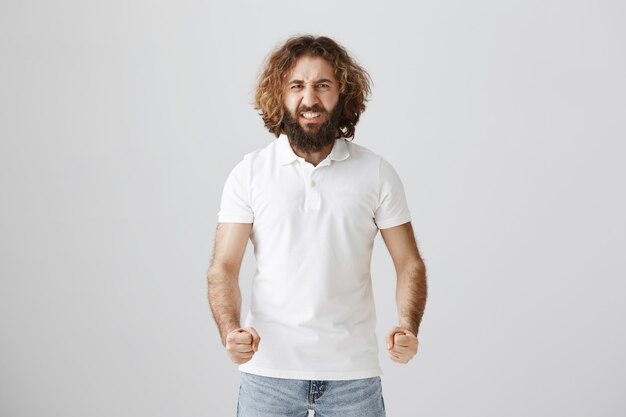 Mad and outrated middle-eastern guy grimacing and clench fists in anger