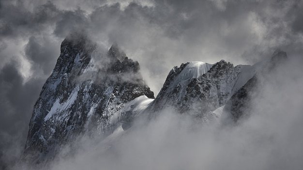 Magical shot of a beautiful snowy mountain peak covered with clouds.