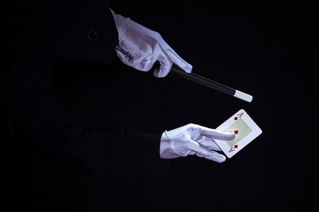 Magician performing trick on aces playing card against black background