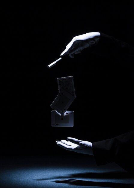Magician performing trick with magic wand against black background