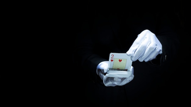 Magician performing trick with playing cards against black background