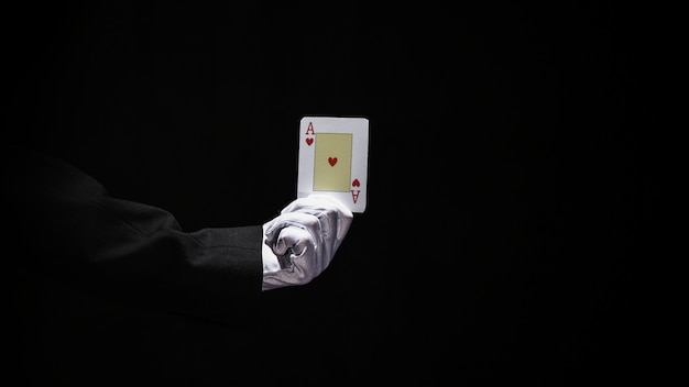 Рука мага, держащая тузы игральные карты на черном фоне