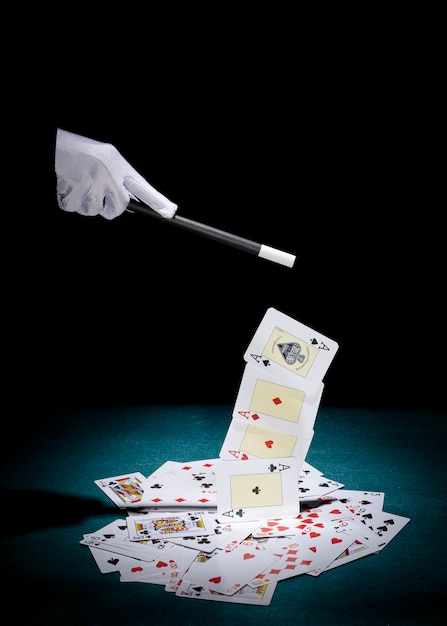 Foto gratuita la mano del mago raccoglie le carte degli assi con la bacchetta magica sul tavolo da poker